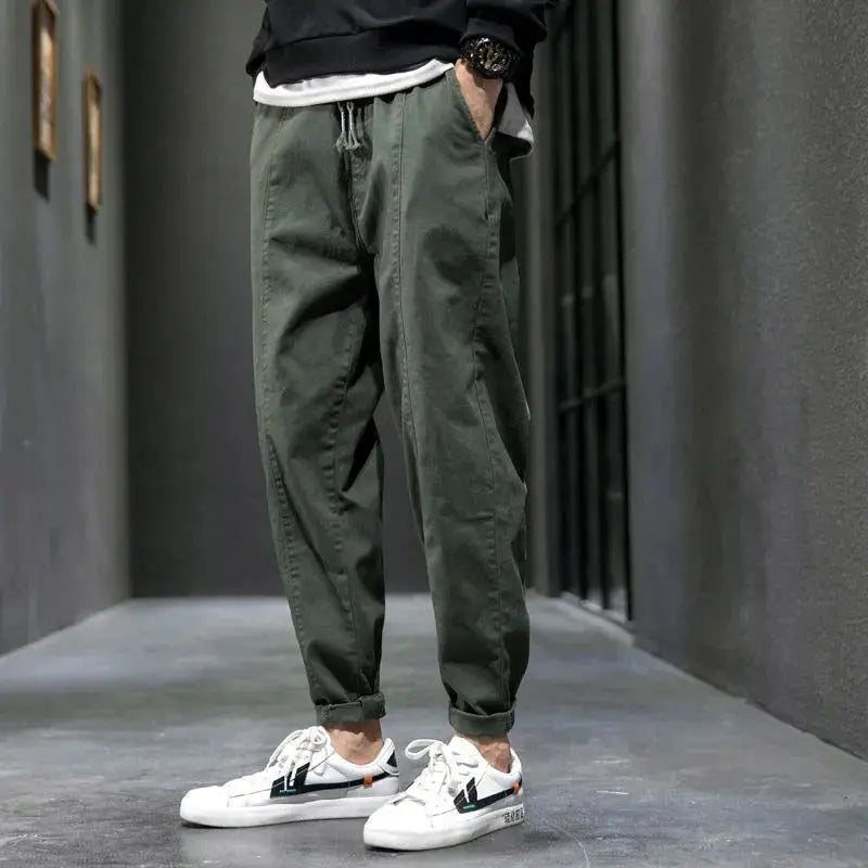 Person wearing green jogger pants and white sneakers in an urban setting