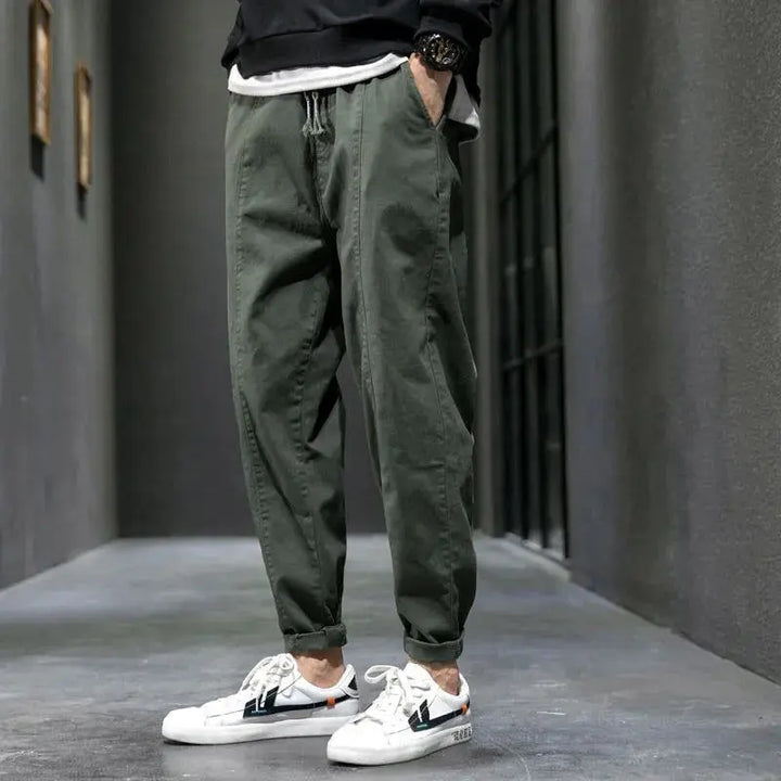 Person wearing green jogger pants and white sneakers in an urban setting