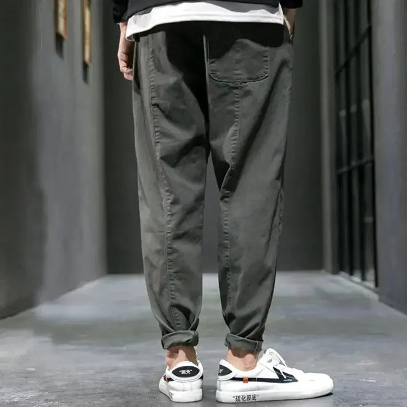 Person wearing dark gray jogger pants and white sneakers on a gray floor.