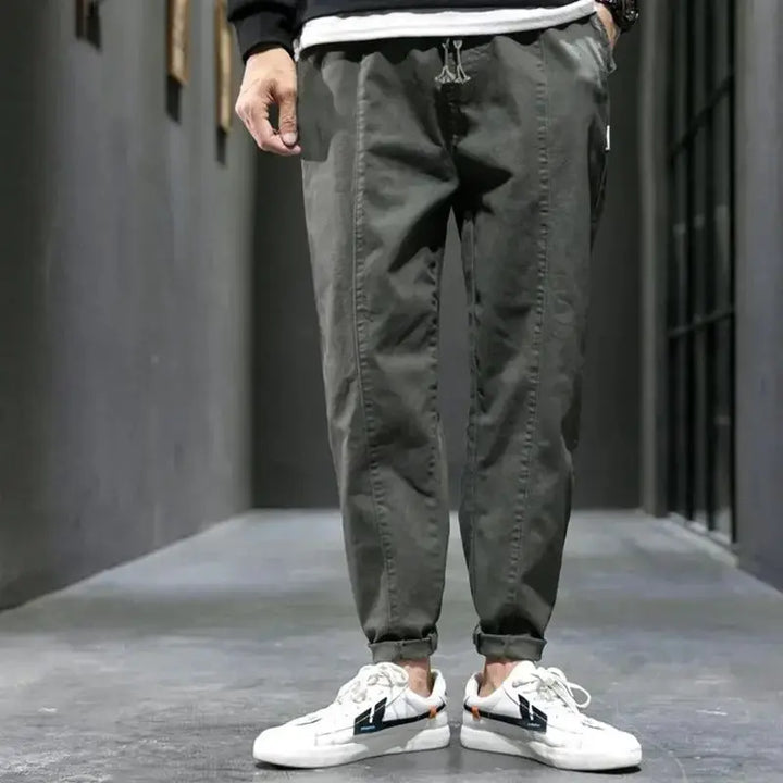 Person wearing gray jogger pants and white sneakers in an urban setting